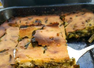 Μια χρυσή, ξεροψημένη χορτόπιτα χωρίς φύλλο κομμένη σε τετράγωνα κομμάτια, όπου διακρίνονται τα χόρτα και η λιωμένη φέτα στο εσωτερικό