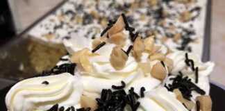 Τούρτα ταψιού με αφράτη λευκή κρέμα, καλυμμένη με σαντιγί και πασπαλισμένη με χοντροκομμένα καβουρδισμένα αμύγδαλα