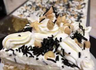 Τούρτα ταψιού με αφράτη λευκή κρέμα, καλυμμένη με σαντιγί και πασπαλισμένη με χοντροκομμένα καβουρδισμένα αμύγδαλα