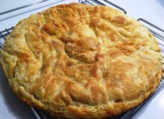 Μια χρυσαφένια, τραγανή σπανακόπιτα με χειροποίητο φύλλο, κομμένη σε τετράγωνα κομμάτια μέσα στο ταψί.