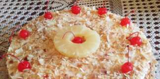 Μια φέτα από τούρτα νουγκατίνα με στρώσεις λευκής μαρέγκας, κρεμώδους γέμισης και κομμάτια ξηρών καρπών.