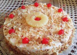 Μια φέτα από τούρτα νουγκατίνα με στρώσεις λευκής μαρέγκας, κρεμώδους γέμισης και κομμάτια ξηρών καρπών.