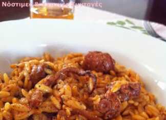 Ένα πιάτο με ζουμερό χταπόδι κοκκινιστό με κριθαράκι σε πλούσια κόκκινη σάλτσα, γαρνιρισμένο με φρέσκο πιπέρι και πάπρικα.