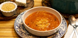 Ένα μπολ με κόκκινη σούπα μανέστρα, με μικρά ζυμαρικά και ψιλοκομμένα μυρωδικά στην επιφάνεια.