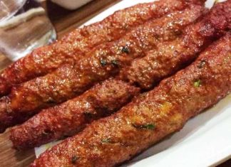 Καλοψημένα σουβλάκια κεμπάπ και πατάτες περασμένες σε ξυλάκια, σερβιρισμένα σε δίσκο με μυρωδικά