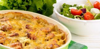 Λουκάνικο με πατάτες και λιωμένο τυρί σε ένα ταψί έτοιμο για σερβίρισμα.