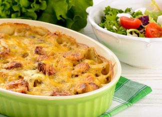 Λουκάνικο με πατάτες και λιωμένο τυρί σε ένα ταψί έτοιμο για σερβίρισμα.