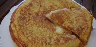 Παχιά ομελέτα σερβιρισμένη σε πιάτο, κομμένη σε τριγωνικά κομμάτια, με το λιωμένο τυρί να φαίνεται στο εσωτερικό.