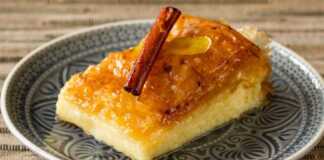 Χρυσαφένιο τραγανό γαλακτομπούρεκο κομμένο σε τετράγωνα κομμάτια που κολυμπάνε σε διάφανο σιρόπι