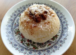 Ένα πιάτο με ένα στρογγυλό, λείο επιδόρπιο σιμιγδάλι, πασπαλισμένο με κανέλα και διακοσμημένο με λίγες νιφάδες καρύδας.