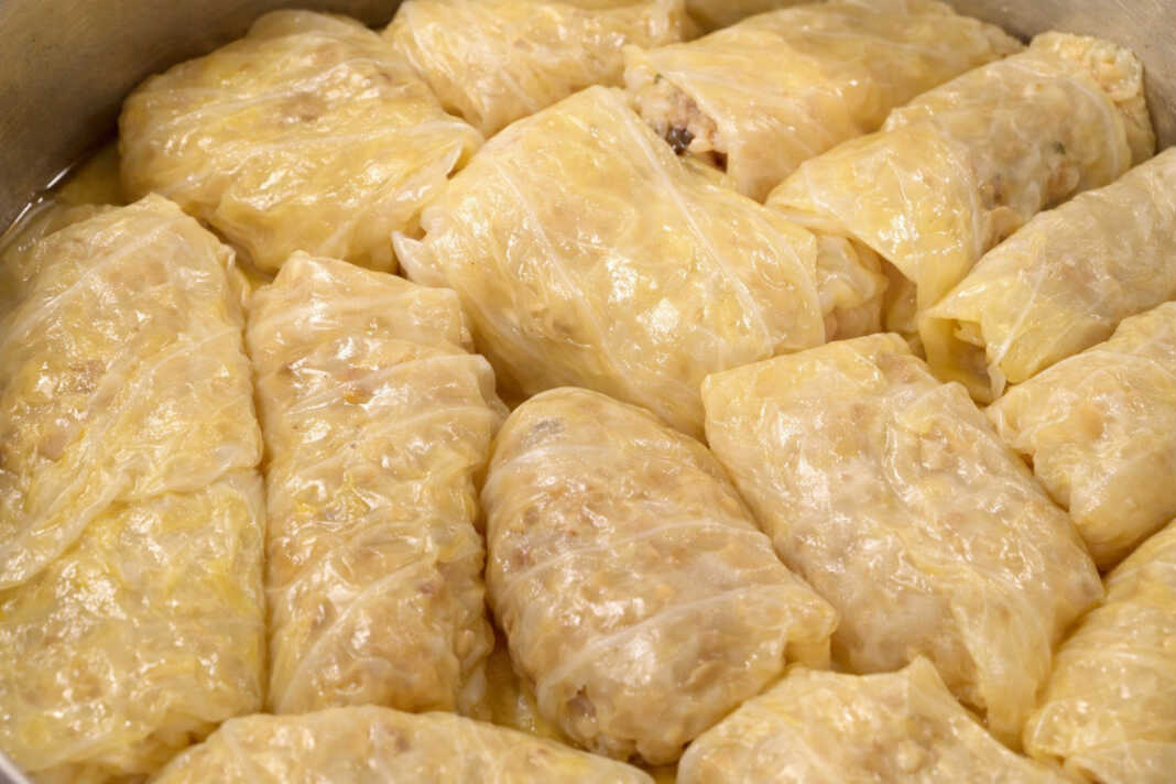 Μια σειρά από καλοτυλιγμένους λαχανοντολμάδες μέσα στην κατσαρόλα, περιχυμένους με ελαιόλαδο και φρέσκα μυρωδικά