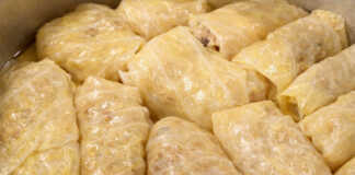 Μια σειρά από καλοτυλιγμένους λαχανοντολμάδες μέσα στην κατσαρόλα, περιχυμένους με ελαιόλαδο και φρέσκα μυρωδικά