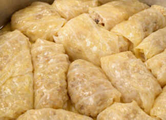 Μια σειρά από καλοτυλιγμένους λαχανοντολμάδες μέσα στην κατσαρόλα, περιχυμένους με ελαιόλαδο και φρέσκα μυρωδικά