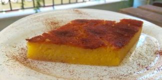 Ένα κομμάτι χρυσαφένιας Λευκαδίτικης γαλατόπιτας με φύλλο, πασπαλισμένη με κανέλα, σε λευκό πιάτο.