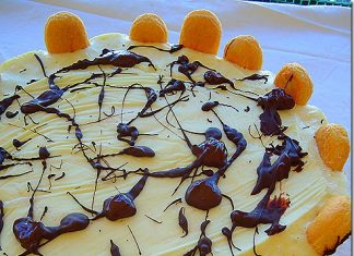 Μια λαχταριστή φέτα από τούρτα παγωτό λεμόνι με σαβουαγιάρ, διακοσμημένη με φέτες λεμονιού και μέντα.