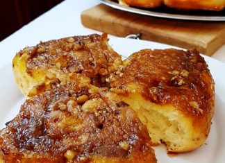 Ζεστά αφράτα ρολάκια με γέμιση μήλου και καρυδιού αναποδογυρισμένα σε δίσκο με λιωμένη καραμέλα και μαύρη ζάχαρη να τρέχει