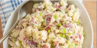 Ενα μπολ με πλούσια, κρεμώδη πατατοσαλάτα, γαρνιρισμένη με φρέσκα μυρωδικά, έτοιμη για σερβίρισμα.