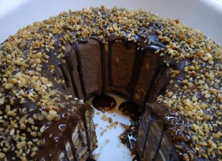 Κέικ μωσαϊκό, με ορατά κομμάτια μπισκότων και σοκολατένια κρέμα, γαρνιρισμένο με τριμμένο φουντούκι.