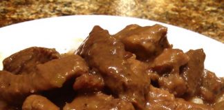 Μοσχαράκι κοκκινιστό με πλούσια, σκούρα κόκκινη σάλτσα, σερβιρισμένο δίπλα σε ρύζι.