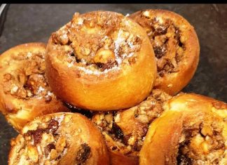 Πιάτο με λαχταριστά Ρολάκια Κανέλας με καρύδια, περιχυμένα με κρέμα βανίλιας και πασπαλισμένα με κανέλα.