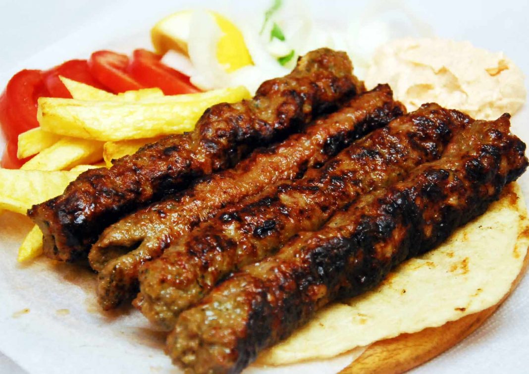 Ζουμερά σπιτικά κεμπάπ, σερβιρισμένα σε πιάτο με πίτες, ψητές ντομάτες, τηγανητές πατάτες και μια μπολ με πικάντικη τυροκαφτερή.