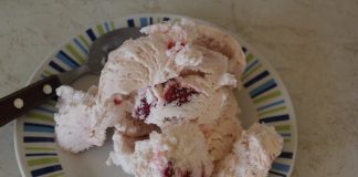 Κοντινό πλάνο ενός μπολ με ροζ σπιτικό παγωτό φράουλα, διακοσμημένο με φρέσκες φράουλες.