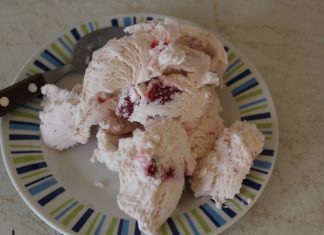 Κοντινό πλάνο ενός μπολ με ροζ σπιτικό παγωτό φράουλα, διακοσμημένο με φρέσκες φράουλες.