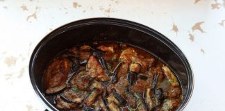 Κοντινό πλάνο στο χοιρινό με μελιτζάνες στη γάστρα, που αναδεικνύει την πλούσια, μελωμένη σάλτσα