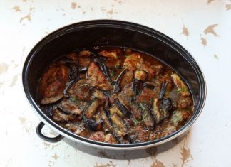 Κοντινό πλάνο στο χοιρινό με μελιτζάνες στη γάστρα, που αναδεικνύει την πλούσια, μελωμένη σάλτσα