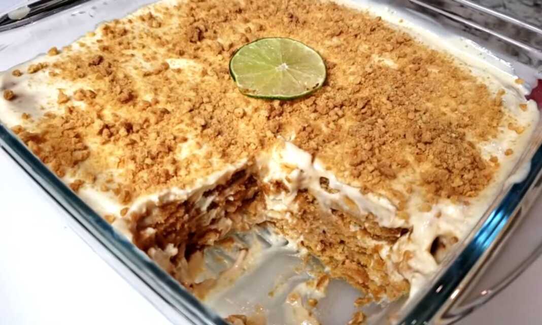 Ένα δροσερό γλυκό ταψιού με στρώσεις μπισκότων και λευκή κρέμα λάιμ πασπαλισμένο με τρίμμα μπισκότου και ξύσμα λάιμ