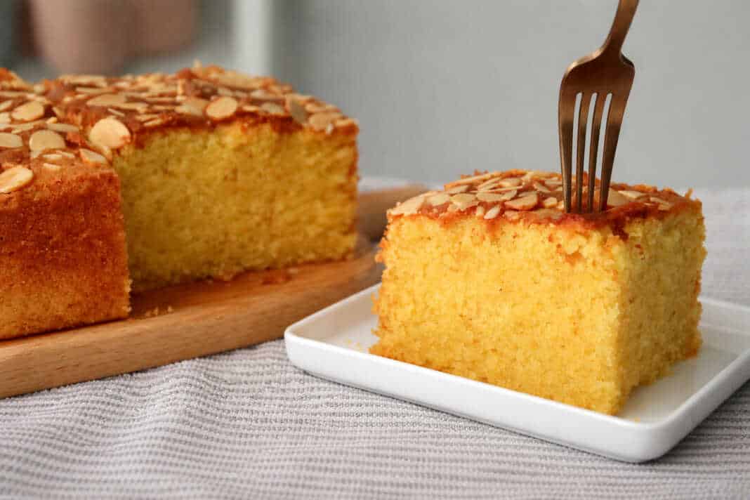 Ζουμερό και υγρό κέικ αμυγδάλου με πορτοκάλι, καλυμμένο με χρυσαφένιες νιφάδες αμυγδάλου σε τετράγωνο ταψί