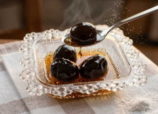 Μαύρα γυαλιστερά καρυδάκια μέσα σε πυκνό σιρόπι, αρωματισμένα με ξυλάκια κανέλας και γαρύφαλλο μέσα σε γυάλινο βάζο