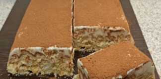 Ένα κομμάτι από γλυκό ψυγείου με γιαούρτι και σπασμένα μπισκότα, πασπαλισμένο με κακάο, σε ένα πιάτο.