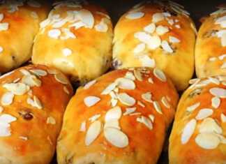 Αφράτα σταφιδόψωμα πασπαλισμένα με φλούδες αμυγδάλου, σερβιρισμένα σε ξύλινη επιφάνεια.