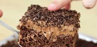 Κομμάτι υγρού κέικ σοκολάτας με πλούσια γυαλιστερή επικάλυψη σοκολάτας και τρούφα σε ένα πιάτο με το σιρόπι να φαίνεται στο εσωτερικό του