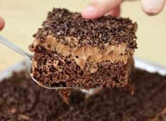 Κομμάτι υγρού κέικ σοκολάτας με πλούσια γυαλιστερή επικάλυψη σοκολάτας και τρούφα σε ένα πιάτο με το σιρόπι να φαίνεται στο εσωτερικό του