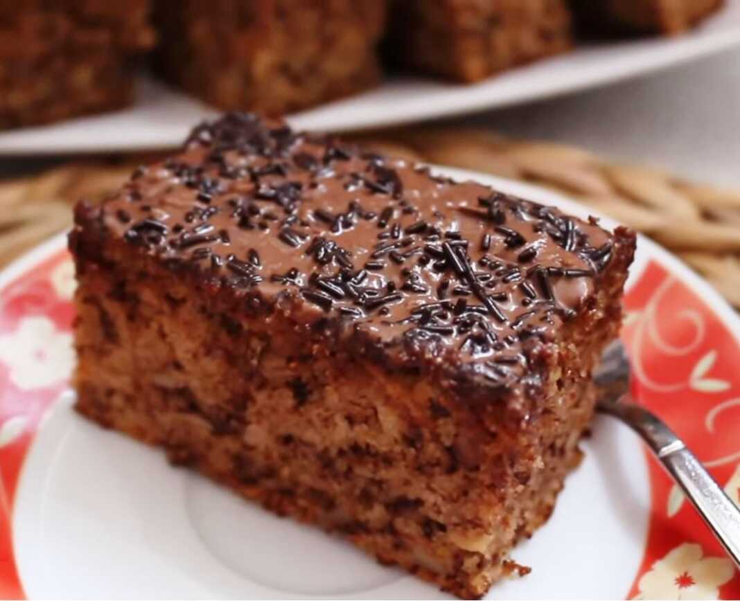 Ένα κομμάτι μηλοκαρυδόπιτας με σκούρο γλάσο σοκολάτας και τρούφα σε ένα άσπρο πιάτο.