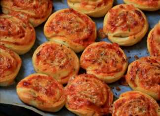 Δίσκος με ρολάκια πίτσας που έχουν ροδίσει ομοιόμορφα με λιωμένο τυρί και ρίγανη να φαίνονται ανάμεσα στις στρώσεις της ζύμης