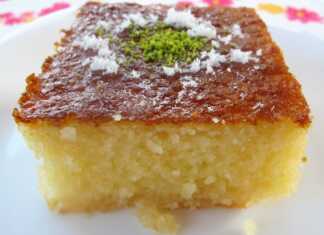 Κομμάτια παραδοσιακού ρεβανί σε τετράγωνα, πασπαλισμένα με τριμμένη καρύδα και γαρνιρισμένα με φιστίκια, λουσμένα με σιρόπι