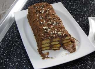 Ένας ολόκληρος σοκολατένιος κορμός με σαβαγιάρ σε μια λευκή πιατέλα, πασπαλισμένος με τριμμένη σοκολάτα ή ξηρούς καρπούς.