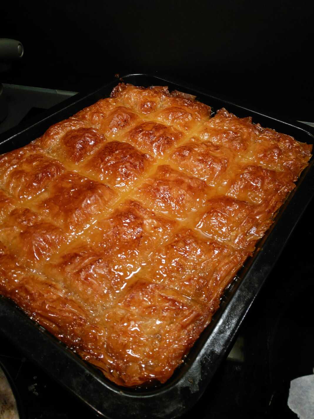 Βασιλικό Γαλακτομπούρεκο, κομμένο σε μερίδες, λουσμένο στο σιρόπι.