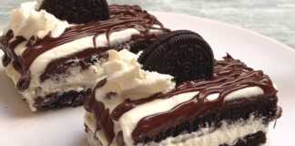 Ένα τετράγωνο κομμάτι γλυκού Oreo με δύο στρώσεις μπισκότου, κρέμα σαντιγί ανάμεσά τους και στην επιφάνεια, διακοσμημένο με λιωμένη σοκολάτα και μισά μπισκότα Oreo.