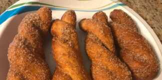 Ένα πιάτο γεμάτο αφράτα κουλουράκια κανέλας, επικαλυμμένα με ζάχαρη και κανέλα, έτοιμα για σερβίρισμα