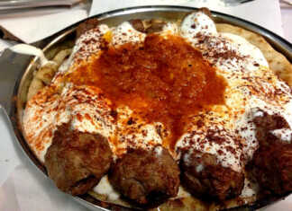 Μια μεγάλη πιατέλα με κομμένες πίτες ζουμερά κεμπάπ κόκκινη σάλτσα και στρώση από γιαούρτι με πάπρικα