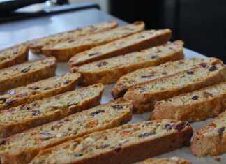 Μακρόστενα τραγανά μπισκότα γεμάτα με κομμάτια αμυγδάλου και αποξηραμένων φρούτων τοποθετημένα πάνω σε αντικολλητικό χαρτί ψησίματος