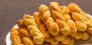 Ένα ταψί γεμάτο με χρυσαφένια, αφράτα κουλουράκια πορτοκαλιού σε διάφορα σχήματα, φρεσκοψημένα.