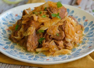 Ζουμερά κομμάτια χοιρινού κρέατος μαγειρεμένα με μελωμένο λάχανο και σάλτσα ντομάτας σε βαθύ πιάτο