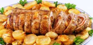 Ζουμερό χοιρινό ρολό κομμένο σε φέτες με ορατή τη γέμιση από πιπεριά και τυρί, περιτριγυρισμένο από ροδοκοκκινισμένες πατάτες φούρνου