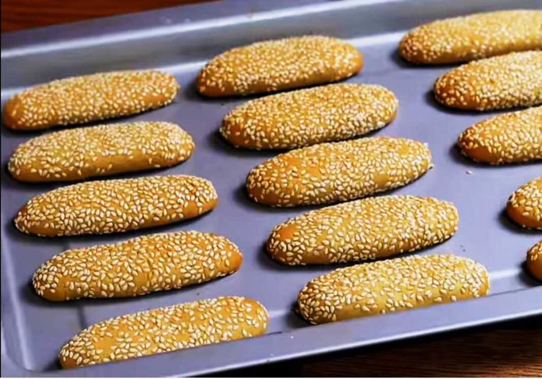 Ένα ταψί με χρυσαφένια, μακρόστενα κουλουράκια πασπαλισμένα με σουσάμι.
