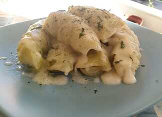 Λαχανοντολμάδες σε πιάτο, περιχυμένοι με πλούσια, κρεμώδη λευκή σάλτσα (αυγολέμονο βελουτέ) και πασπαλισμένοι με άνηθο.